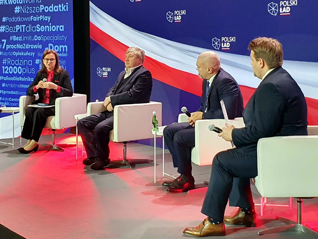 paneliści na konferencji - prezes ZUS i 3 mężczyzn siedzą na tle baneru Polski Ład.  link do powiększonego zdjęcia